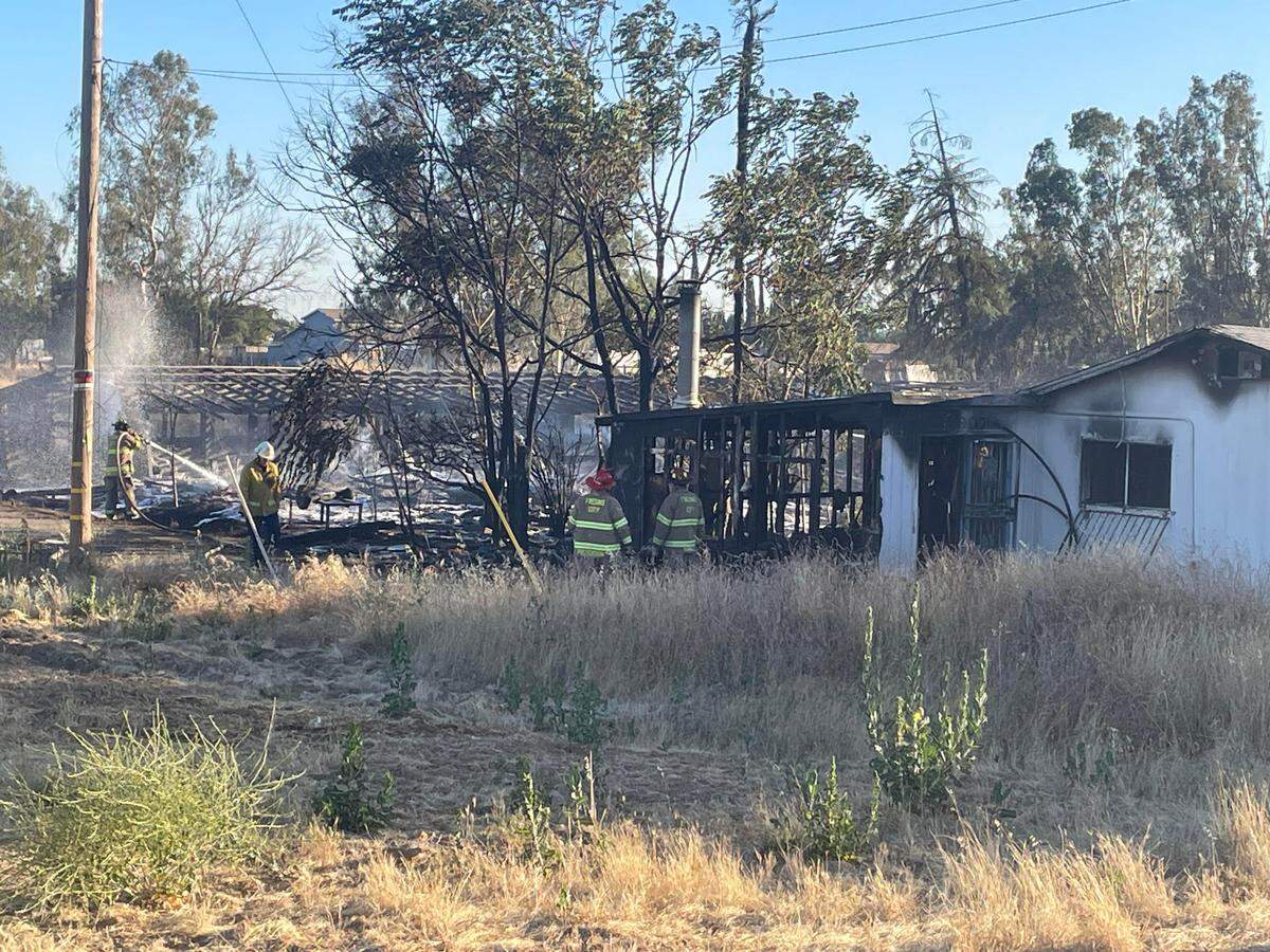 Firefighters mop up after a fire erupted in several sheds, then moved to a home Tuesday night in northwest Fresno.