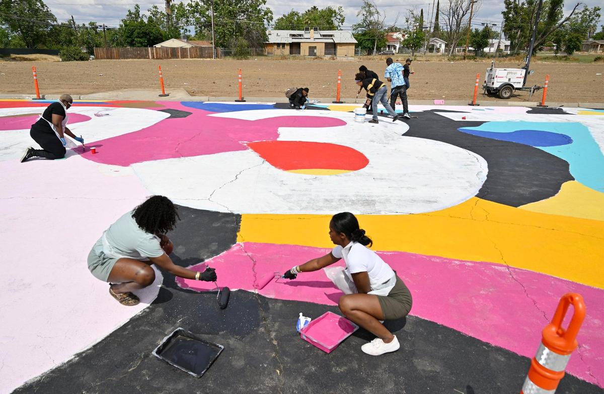 Volunteers gathered to help paint a large street mural along Klette Avenue just north of California Ave. as part of the West Fresno California Avenue Neighborhood (CAN) initiative Saturday, May 6, 2023 in Fresno. Area residents and artists gathered to paint the permanent mural as part of a revitalization effort.