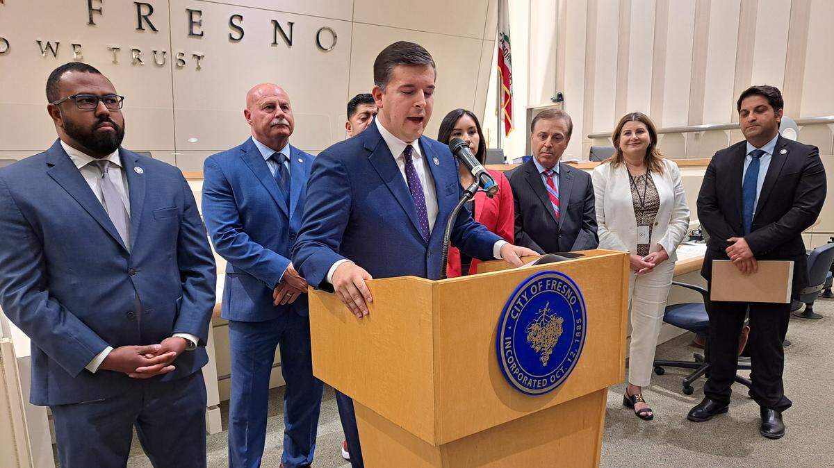Fresno City Council President Tyler Maxwell, at microphone, discusses the city’s $1.87 billion budget that won unanimous City Council approval on Thursday, June 22, 2023. Flanking Maxwell are (from left), Councilmember Nelson Esparza, Mayor Jerry Dyer, Councilmembers Luis Chavez, Annalisa Perea and Garry Bredefeld, City Manager Georgeanne White, and Councilmember Mike Karbassi.