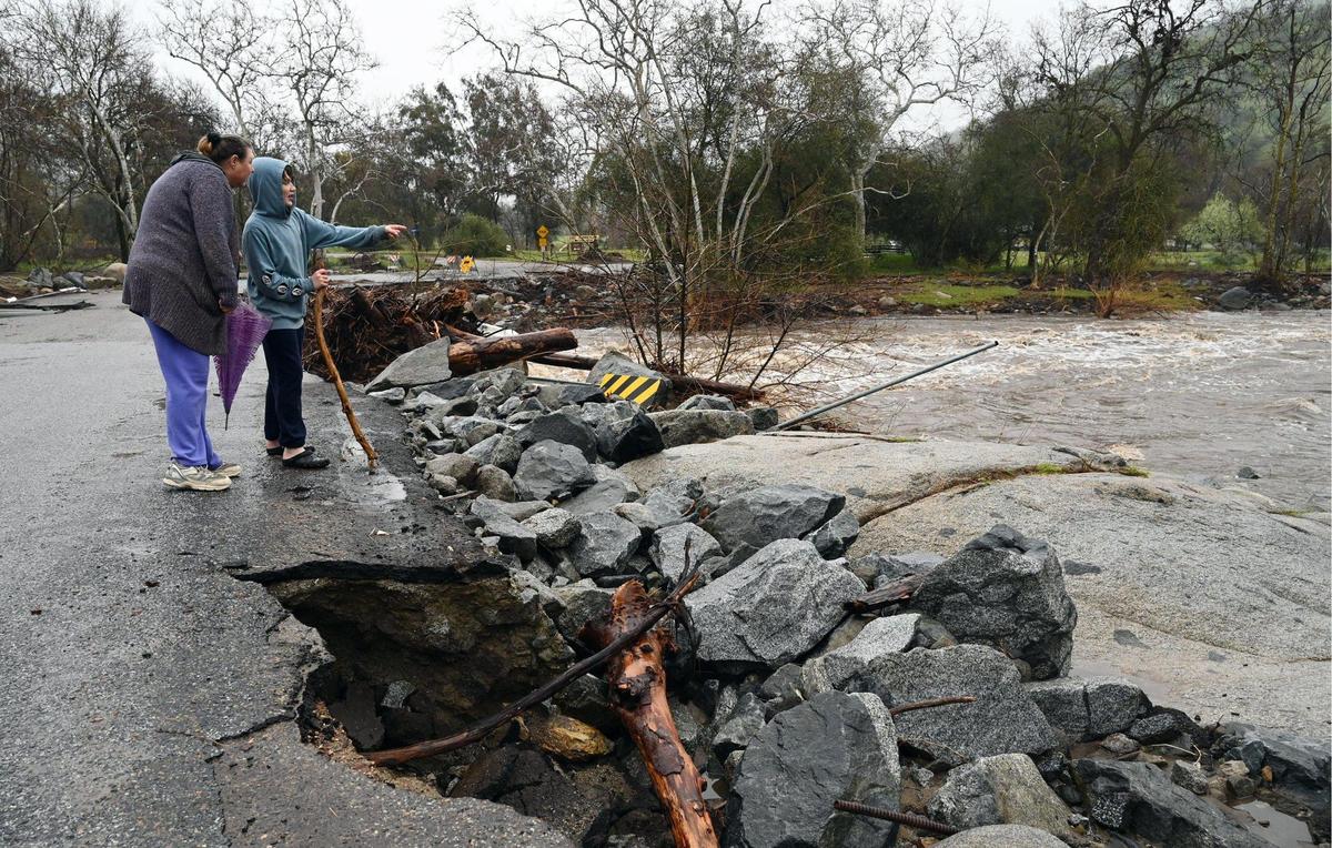 Andrea Holscher, left, with her son, views the raging North Fork of the Kaweah River along Kaweah Drive, closed due to damaged Tuesday, March 14, 2023 near Three Rivers.