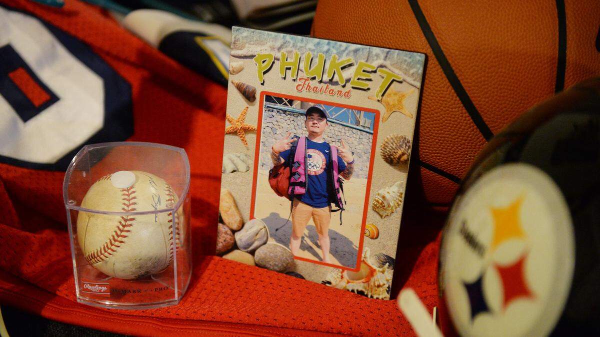 Phia Vang is seen in a photo from his visit to Phuket, Thailand, as it sits among sports memorabilia he had collected over the years. Phia was one of four killed in a mass shooting Sunday.