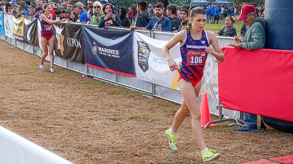 Buchanan’s Kynzlee Buckley, right, crosses the finish as teammate Grace Hutchison tries to keep going after collapsing just short of the finish in the Central Section girls Division 1 cross country race at Woodward Park in Fresno on Thursday, Nov. 17, 2022. Hutchinson finished second to Buckley.