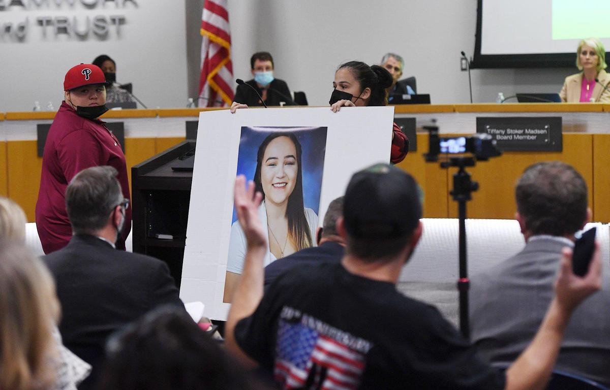 An angry Rosalinda Mendez, right, holds up a photo of her daughter Emi Fair, 16, in an example of her outfit which was was rejected for the yearbook due to the dress code, while her son Cesar Fair is seen to the left at the Clovis School Board meeting Wednesday night, Nov. 10, 2021 in Clovis.