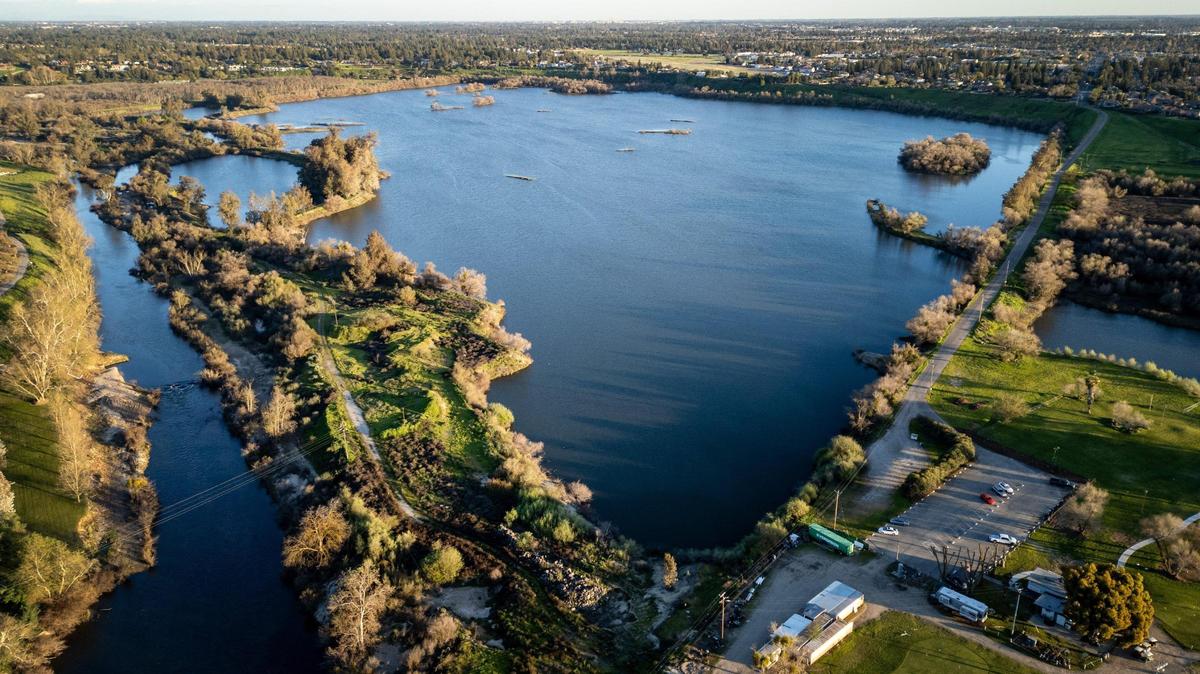Largas sombras se proyectan sobre Milburn Pond, en el centro, y el norte de Fresno, al fondo, mientras el río San Joaquín, a la izquierda, fluye hacia el oeste cerca del campo de golf y el centro de aprendizaje Bluff Pointe, abajo a la derecha, el jueves 14 de marzo de 2024.
