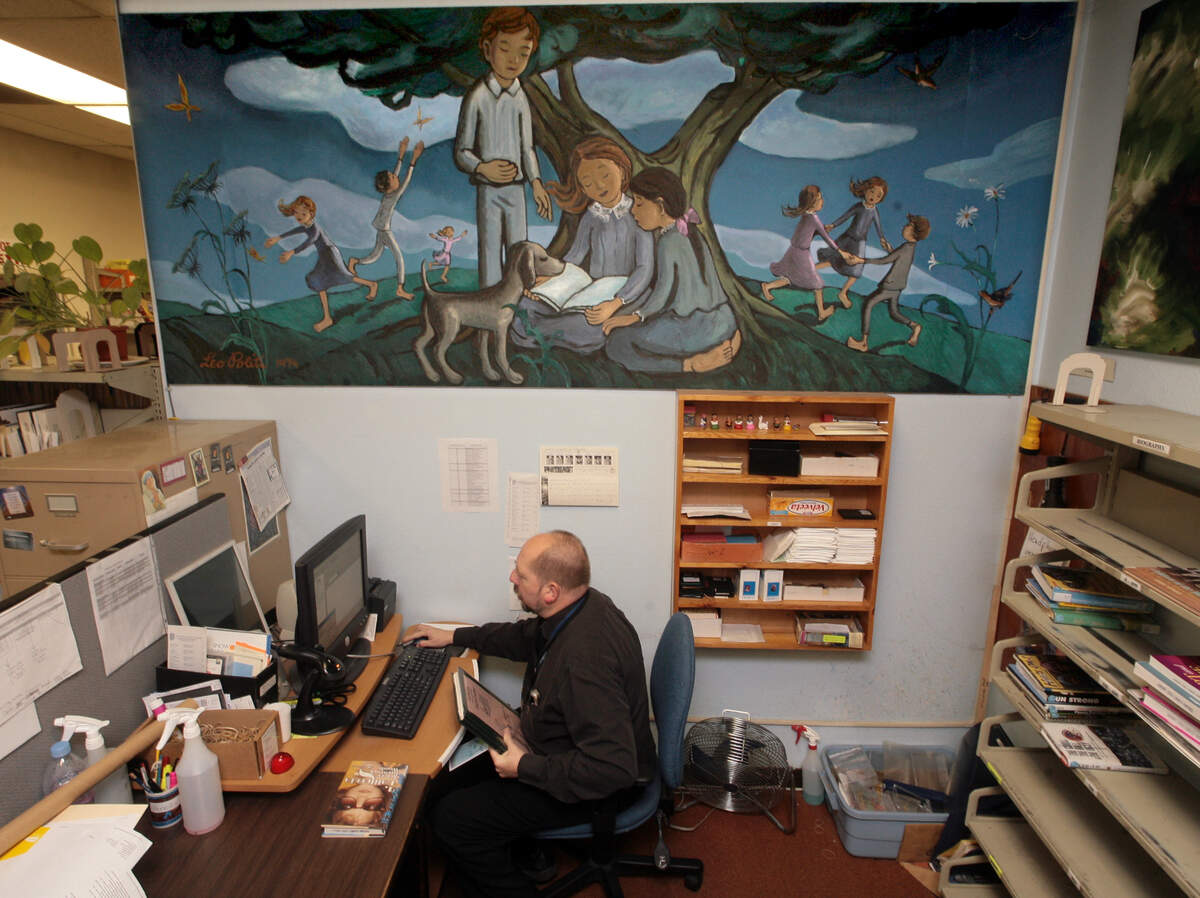 In this staff file photo from Dec. 17, 2007, librarian Terrance McArthur sits beneath a large mural by the late Leo Politi at the Leo Politi branch of the Fresno County Library.