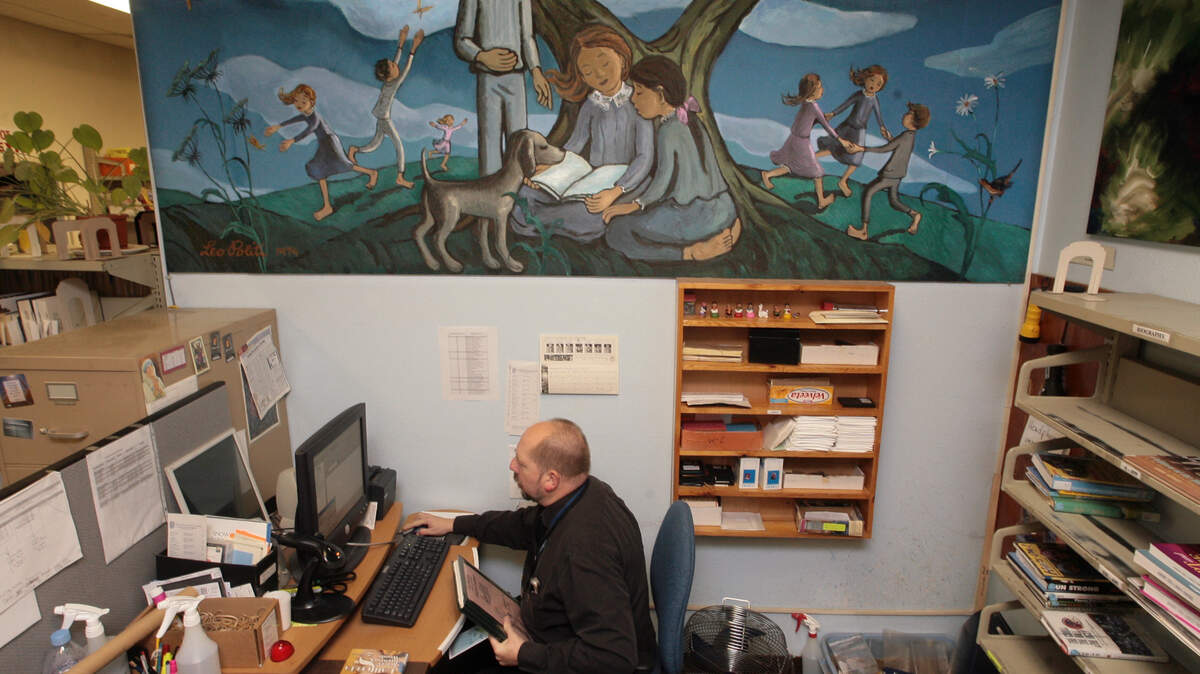 In this staff file photo from Dec. 17, 2007, librarian Terrance McArthur sits beneath a large mural by the late Leo Politi at the Leo Politi branch of the Fresno County Library.