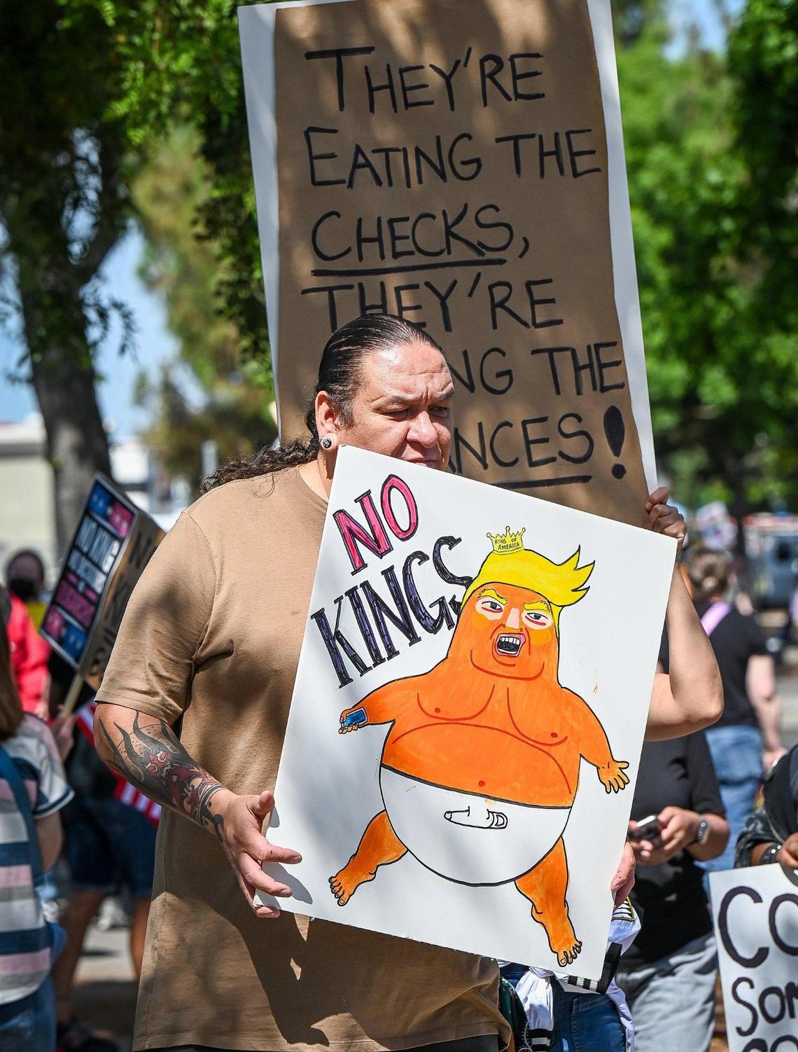 A protester carries an anti-Trump sign in front of Fashion Fair Mall in Fresno during a “No Kings” protest against President Donald Trump’s policies on Saturday, June 14, 2025.
