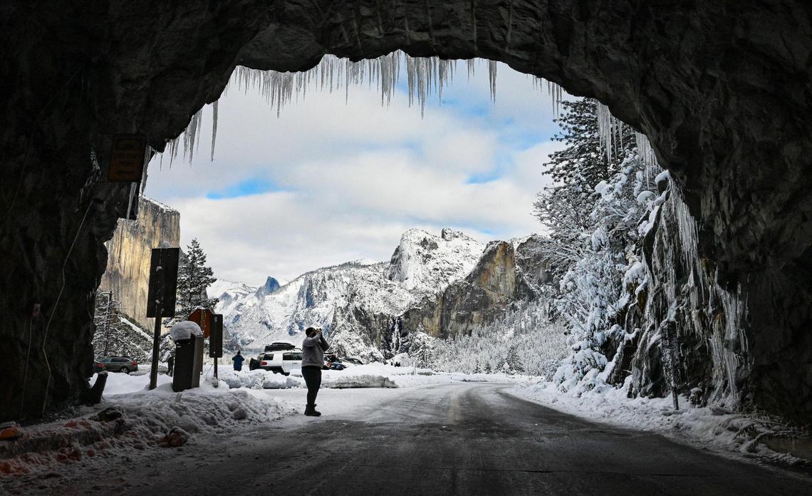 A photographer gets a shot of the icicles hanging from the opening of the tunnel at Tunnel View in Yosemite on Wednesday, Dec. 15, 2021, following a snowstorm the day before.