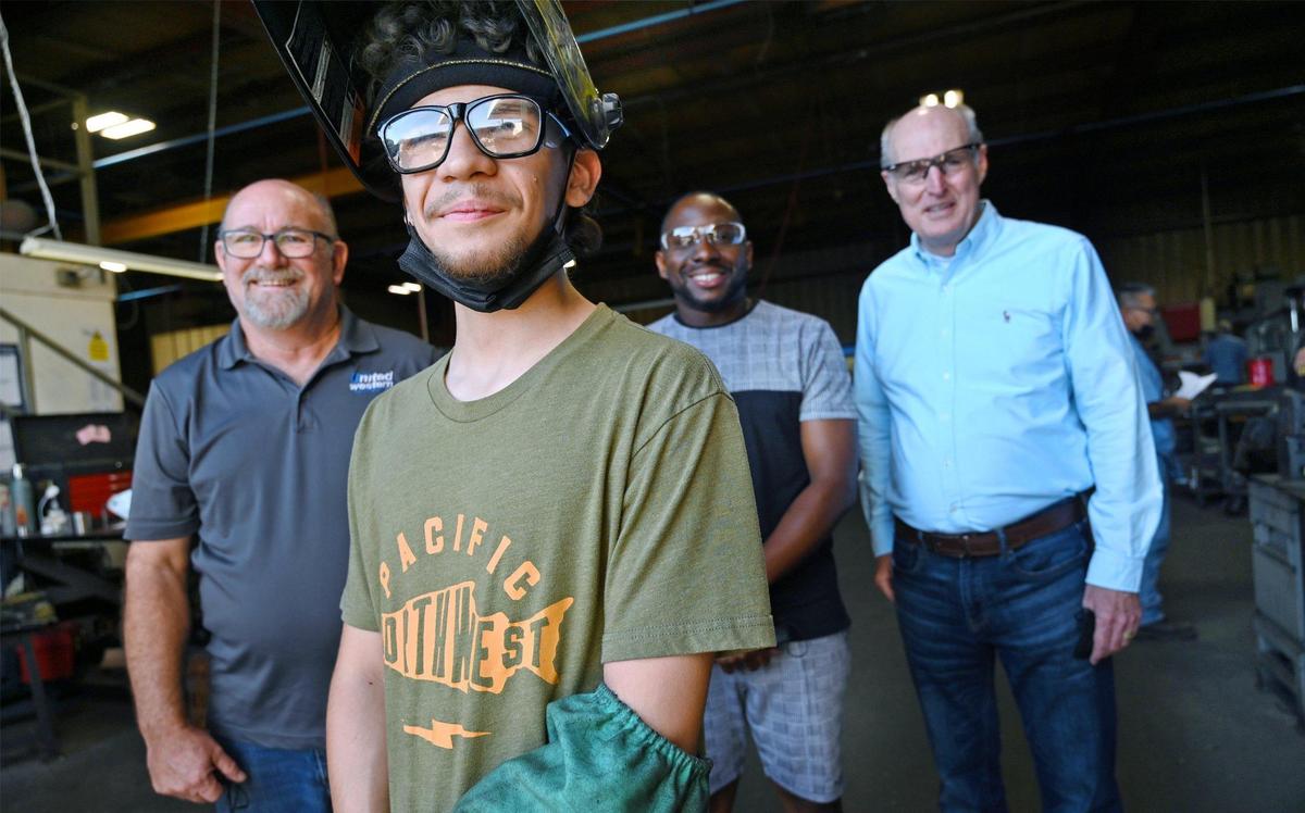 Carlos Martinez-Ramos, second from left, is seen with Bruce Ketch,general manager at Career Nexus, left, Timothy Lowe, internship manager at Career Nexus, second from right, and Kurt Madden, far right, CEO of Career Nexus, at United Western Industries where Martinez-Ramos works as a welder, Friday, July 1, 2022 in Fresno. Carlos graduated from a work training program supported by Career Nexus, which placed him at United Western. Bruce Ketch, general manager at United Western was so impressed, the company hired him full-time.