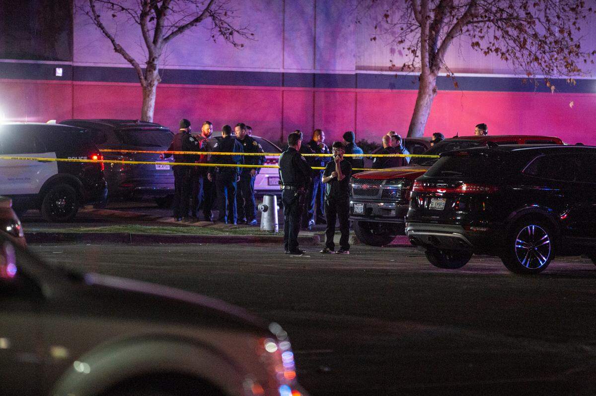 Fresno police officer speaks with a person who was inside the Bowlero bowling alley during a fatal shooting on Friday, Feb. 11, 2022.