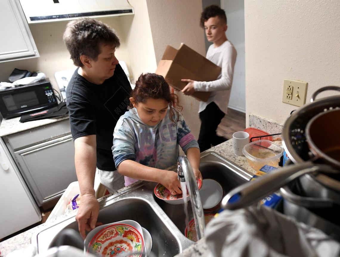 Eight-year-old Santana Smithfield helps her mother, Ginger Smithfield, wash dishes as Ginger’s 13-year-old son, Andrew Greenfield, brings in a box to prepare for leaving their Fresno apartment Tuesday Feb. 9, 2021. The family is being evicted on Feb. 10; Ginger Smithfield, a working mother of four, is hoping for motel vouchers to get them by. Otherwise, they’ll be on the street. Her plans beyond that are to move to Mexico since she says she can’t afford to live in the U.S.