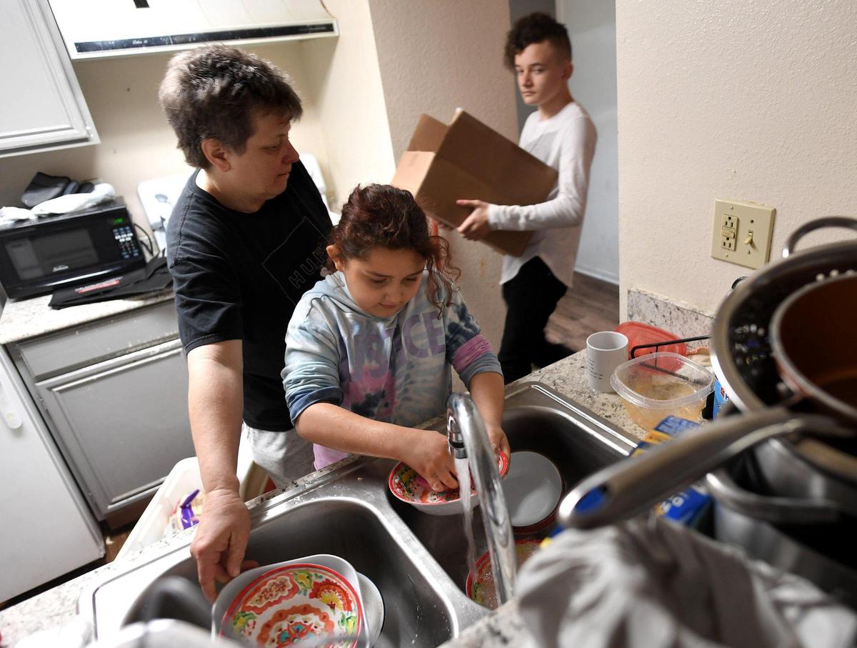 Eight-year-old Santana Smithfield helps her mother, Ginger Smithfield, wash dishes as Ginger’s 13-year-old son, Andrew Greenfield, brings in a box to prepare for leaving their Fresno apartment Tuesday Feb. 9, 2021. The family is being evicted on Feb. 10; Ginger Smithfield, a working mother of four, is hoping for motel vouchers to get them by. Otherwise, they’ll be on the street. Her plans beyond that are to move to Mexico since she says she can’t afford to live in the U.S.