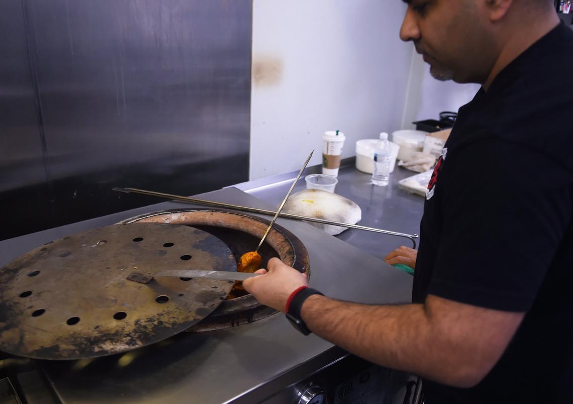 Goldie Bedi closes a tandoori oven as Chicken Tikka cooks within at Bollywood Indian Street Food Wednesday, Feb. 20, 2019 in Fresno.