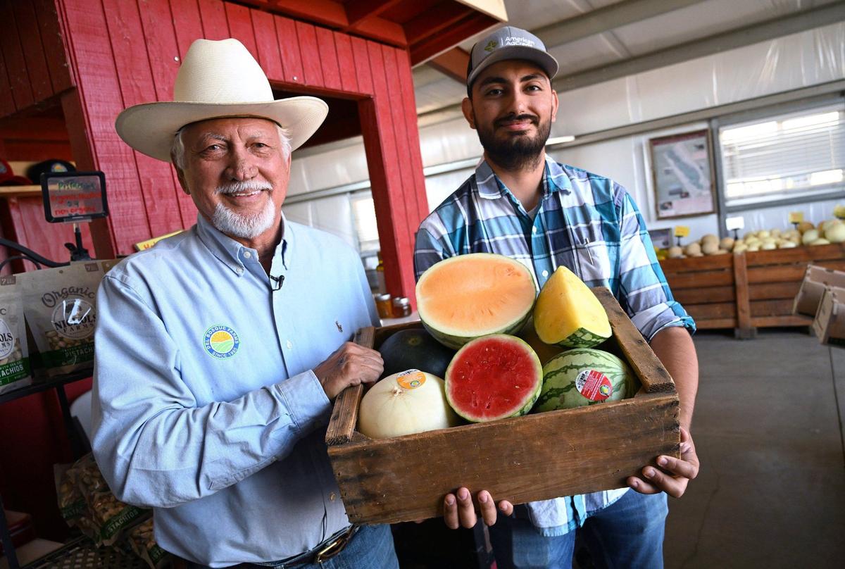 Joe Del Bosque, left, with Erik Alfaro, right, show off just a small selection of melons the family sells at its fruit stand on Shields Ave near I-5 at the far west side of the Valley Monday, July 15, 2024.