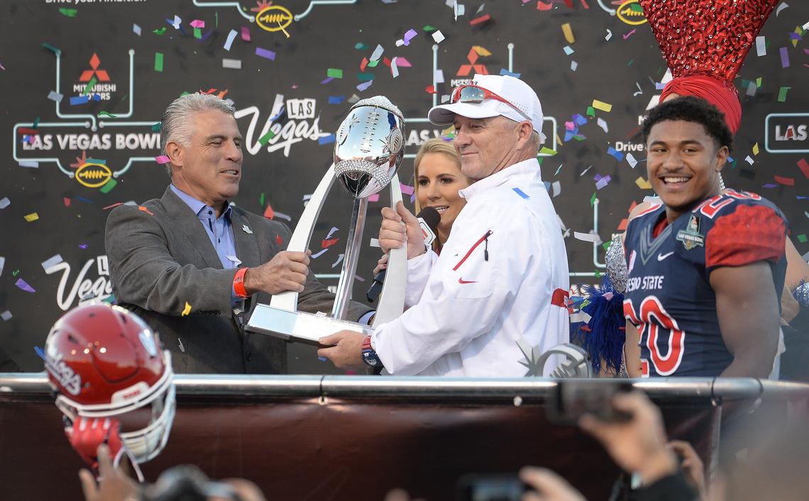 Fresno State coach Jeff Tedford, center, accepts the Las Vegas Bowl championship trophy near MVP Ronnie Rivers, right, during a post-game presentation following the Bulldogs’ 31-20 victory over Arizona State in the Las Vegas Bowl at Sam Boyd Stadium in Las Vegas on Saturday, Dec. 15, 2018.