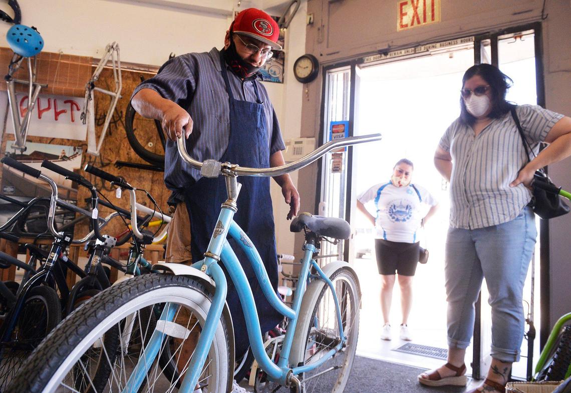 David De La Torre, left, estimates repair work for Roxanne Martinez’ beach cruiser at his new bike shop Dave’s Street Customs Bike Shop Wednesday, May 27, 2020 in Fresno. Dave, whose shop focuses on used bikes, said the COVID19 pandemic has increased business.