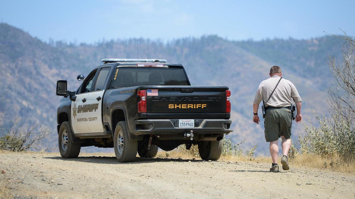 A Mariposa County deputy sheriff stands watch over a remote area northeast of the town of Mariposa, on Wednesday, Aug. 18, 2021. The area is reported to be where a family and their dog was found dead on Tuesday, the Mariposa County Sheriff’s Office said.