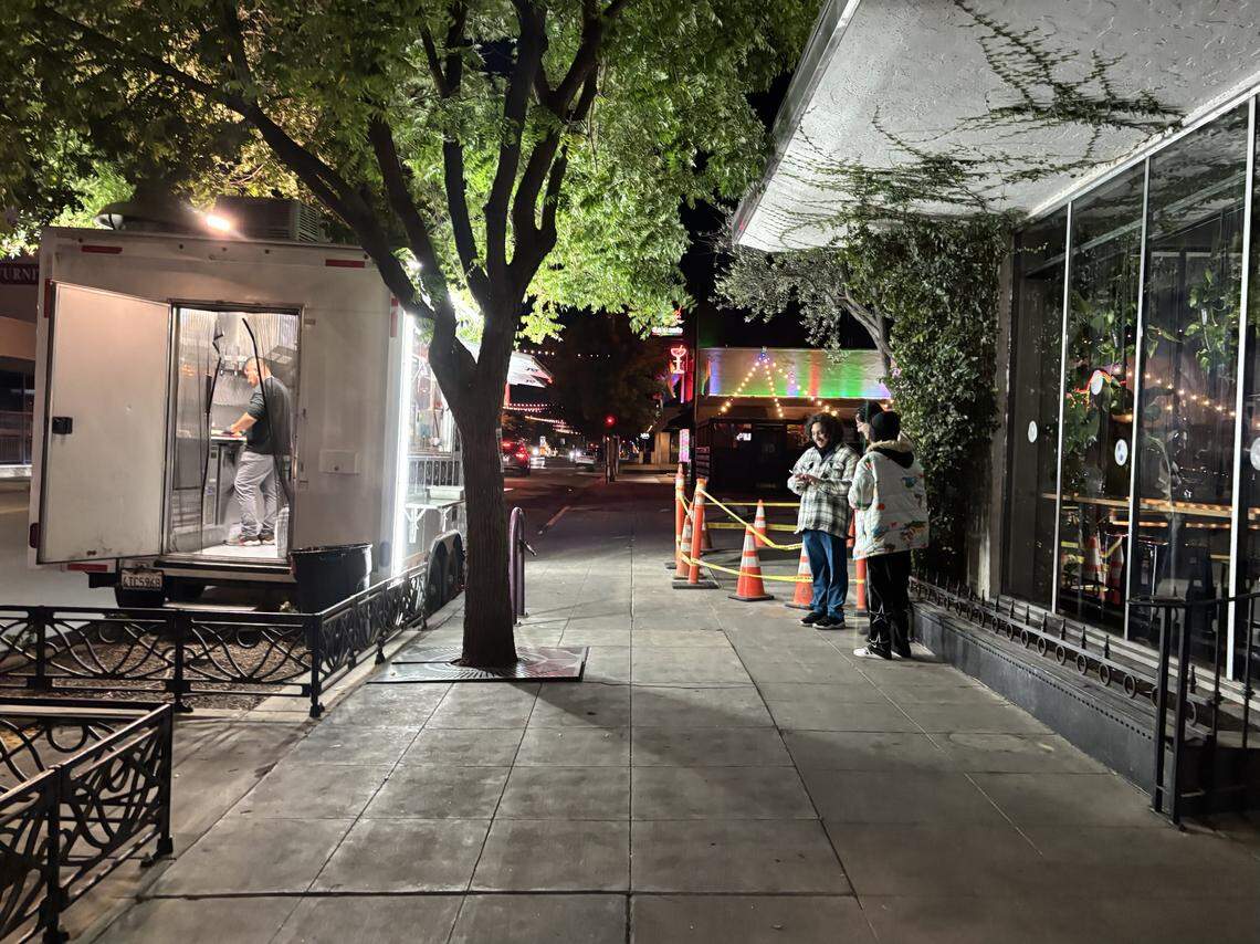 Customers wait for their taco order from Casa del Sazon taco truck, left, on Olive Avenue in Fresno’s Tower District on Wednesday, Oct. 16, 2025.