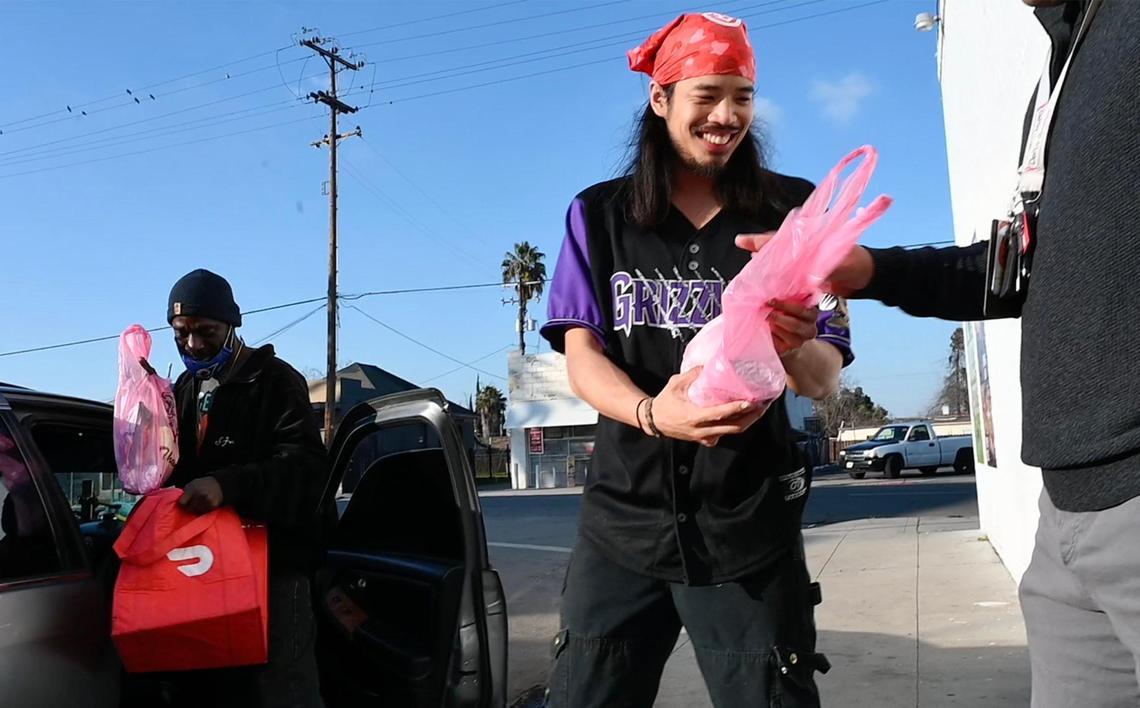 Eddie Wutangsy, center, delivers food to customers waiting outside his My Guy Market, a ghost kitchen along Belmont Avenue just north of downtown that purposes itself as an online app-driven bodega for customers, offering New York City-inspired food and more. Photographed Friday, Jan. 20, 2023 in Fresno.