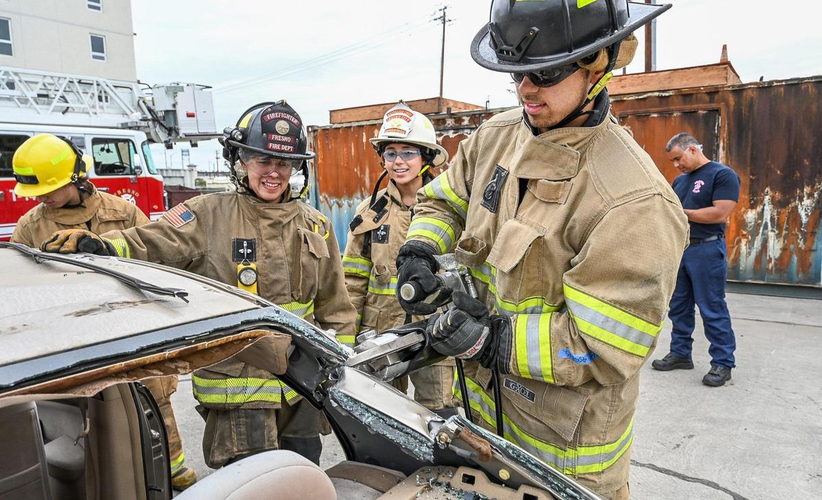 Elijah Dandridge, right, uses a hydraulic cutter while learning extrication techniques on a vehicle with his sister Alexa Dandridge, center, and Fresno firefighter Bailey O’Dell during the Fresno Fire Department’s annual “Firefighter for a Day” event where citizens can get an inside look at the job of a firefighter, at the department’s training grounds in Fresno on Saturday, Oct. 22, 2022.