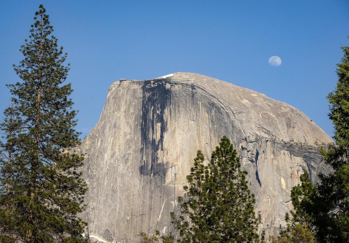 A nearly full moon rises behind Yosemite National Park’s famous Half Dome on a spring day on Friday, April 23, 2021.