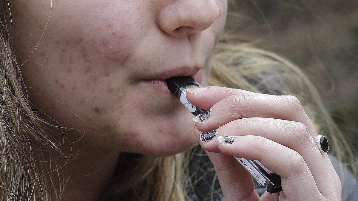 In this April 11, 2018, file photo, a high school student uses a vaping device near a school campus in Cambridge, Mass. Cities and communities in San Luis Obispo County received an "F" rating from the American Lung Association in January 2022 for failing to restrict sales on flavored tobacco. 