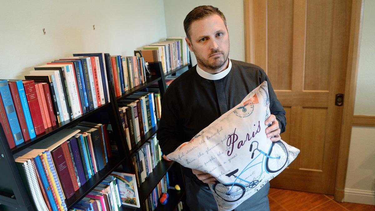 The Very Reverend Ryan D. Newman, an Episcopal Priest and the Dean of the Episcopal Cathedral in Fresno, holds up an accent throw pillow he ordered from Walmart.com that includes graphics of Nazi swastikas and eagles and partial images of an Adolf Hitler postage stamp, at his office in Fresno on Tuesday, Feb. 5, 2019.