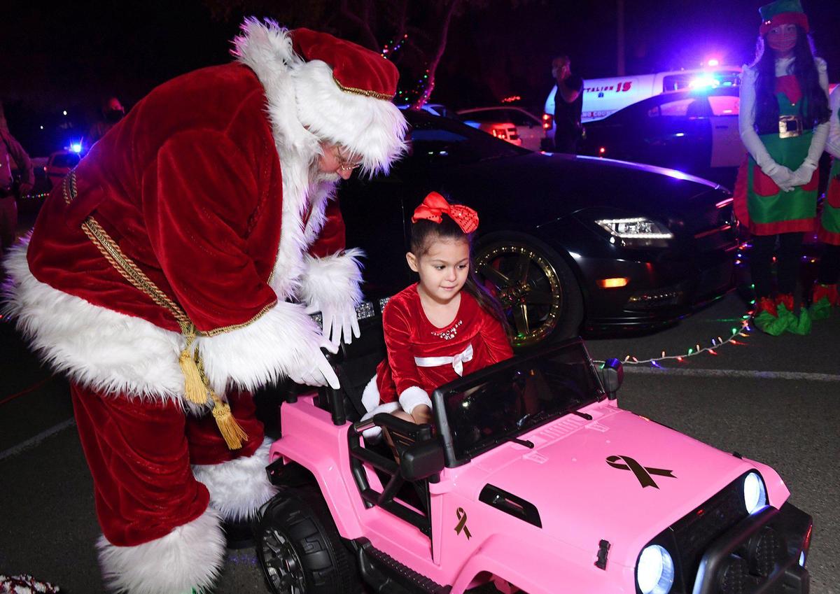 Arianna Jasso, age 6, experiences a special surprise early Christmas, possibly her last, as Santa helps her into her new car at Woodward Park Saturday night, Nov. 21, 2020 in Fresno. Arianna was diagnosed July 20 with a brain tumor called diffuse intrinsic pontine glioma (DIPG) which carries a life expectancy post-diagnoses of six to nine months.