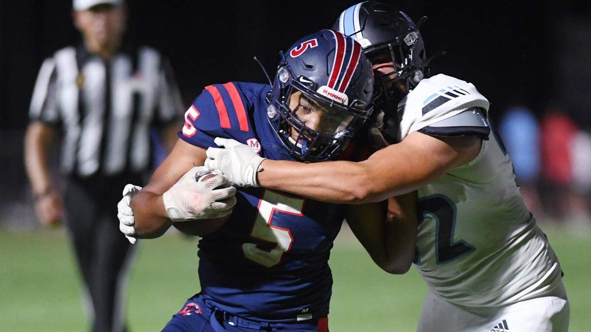Clovis North’s Mario Gonzalez, right, tries to tackle San Joaquin Memorial’s Ty Morgan, left, Friday, Aug. Memorial went on to win 34-0 to kick off the 2022 football season.