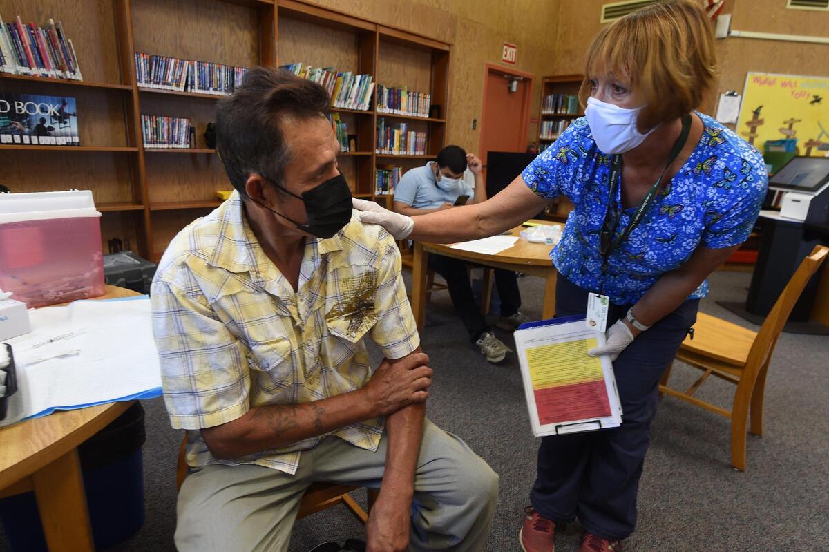 Tulare County Health Dept. RN Cynthia Norvill talks with dairy worker Jose Mariscal after he received his first Covid vaccination, during a clinic at the Tipton Library, July 29, 2021. Only one of two vaccine recipients at the clinic as of midday, he has become worried about the spread of the disease and was doing it to protect his family.