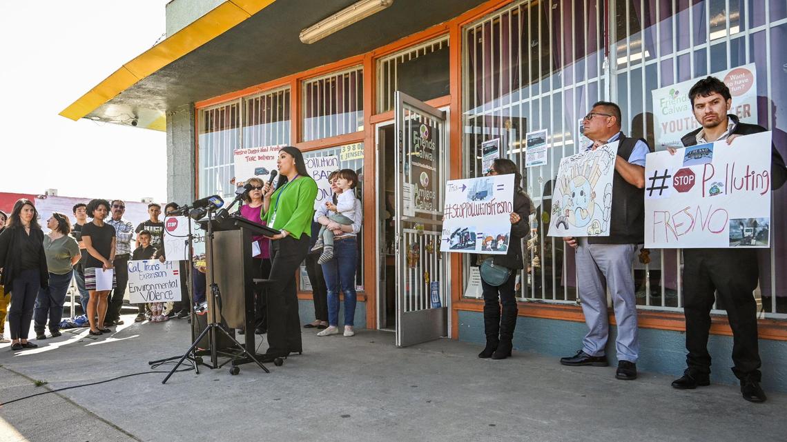 Edith Rico, at lectern, project director for Fresno Building Healthy Communities, begins a press conference to push for stopping an interchange expansion project on Highway 99 in south central Fresno, during a rally with residents on Thursday, April 6, 2023 in front of the Friends of Calwa building in Calwa.