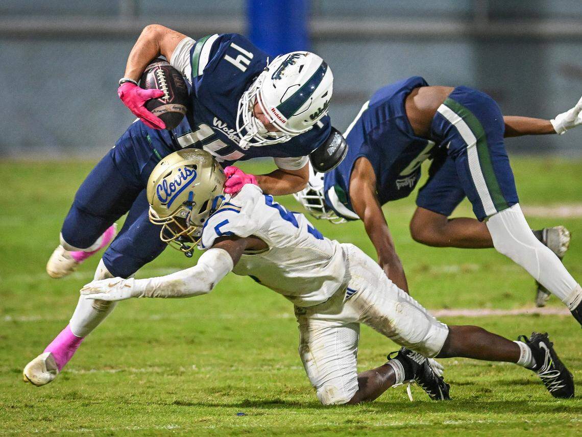 Clovis' Sterling Edwards, center, puts a hit on Clovis East's Elijah Wilson for a tackle on short yardage during their game at Lamonica Stadium in Clovis on Friday, Oct. 17, 2025.