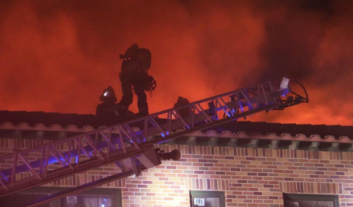 Fresno Fire firefighters climb to the roof as they respond to a fire at the historic Osage Apartments building late Saturday night, Oct. 15, 2022 in Fresno.