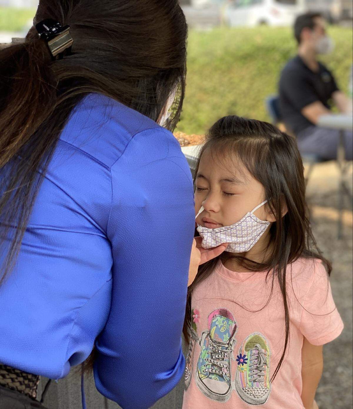 A young girl is swabbed for COVID-19 by her aunt at the UCSF Fresno COVID-19 Equity Project mobile testing site at First 5 Fresno County.