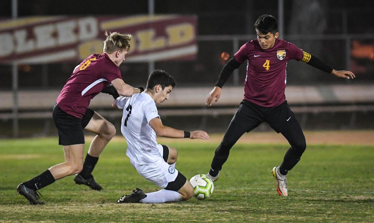 Clovis North’s Samuel Gevorgyan, center, lunges at the ball between Clovis West’s Jake Calmes, left, and Luis Cruz during their game against Clovis West at Tice Park in Fresno on Friday, Jan. 28, 2022.