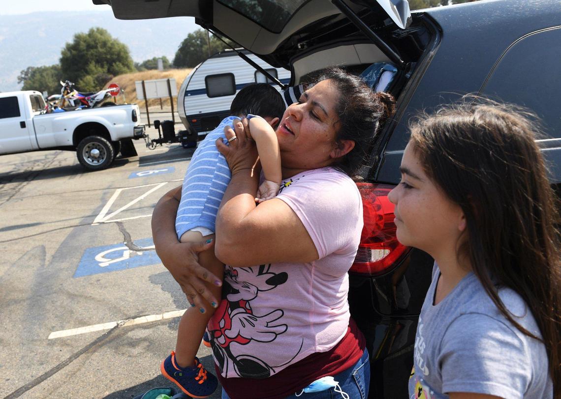 Jacqueline Rodriguez, center, lifts her son Mateo Rodriguez, 1, as Izabella Rodriguez, 10, stands to the right as residents are evacuated and roads closed for a wildfire Saturday, Sept. 5, 2020 near Shaver Lake. The fire, reported at about 2,000 acres and zero containment, was reported Friday night around 6:30 p.m.