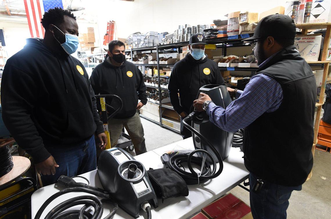 Wendell Pascacio, right, conducts a ChargerHelp! training session on an electric vehicle charging station for technicians, from left, Clyde Ellis, Carlos Aranibar and Marshawn Porter on Thursday, Feb. 11, 2021 at the company’s Fresno warehouse.
