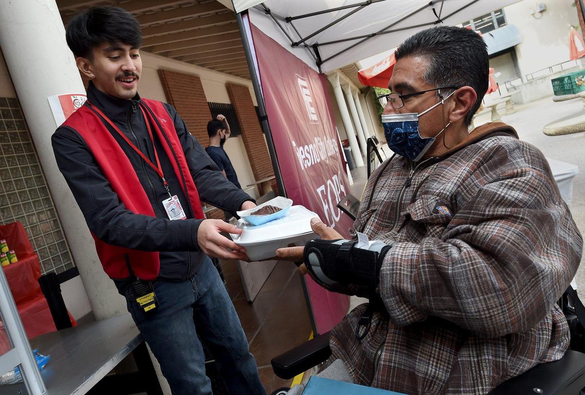 Fresno City College student and Ram Pantry worker Essai Martinez, left, serves up a free hot lunch of Tex-Mex food to student Angelo Mendoza, Nov. 18, 2021. The program that teams up the Ram Pantry and students in the university’s Food Service Management class in giving students studying to become chefs the opportunity to help out other students in need with food insecurities.