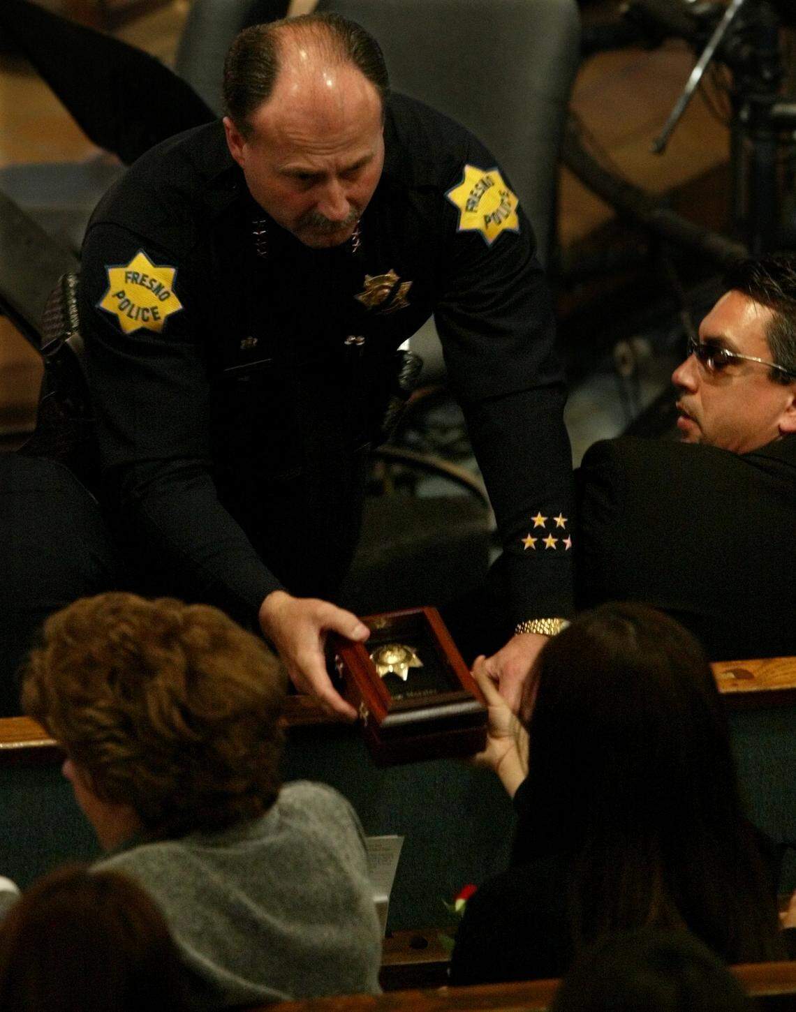 Fresno Police Chief Jerry Dyer presents Kaelyn Moralez a Fresno Police badge in honor of her father, Jose Moralez, during his funeral service. Dyer presented several to various family members during the “Presentation of Badges” ceremony on Dec. 6, 2004.