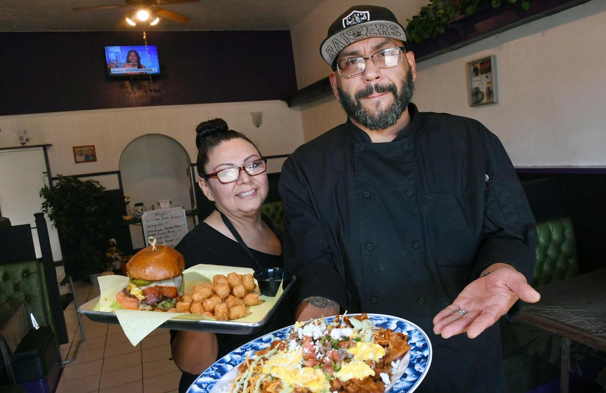 Owner and chef Marcial Gonzalez, right, holding a plate of chilaquiles, stands with his wife Michelle Gonzalez, left, holding their west side burger. They own Grandma Jane’s Kitchen.