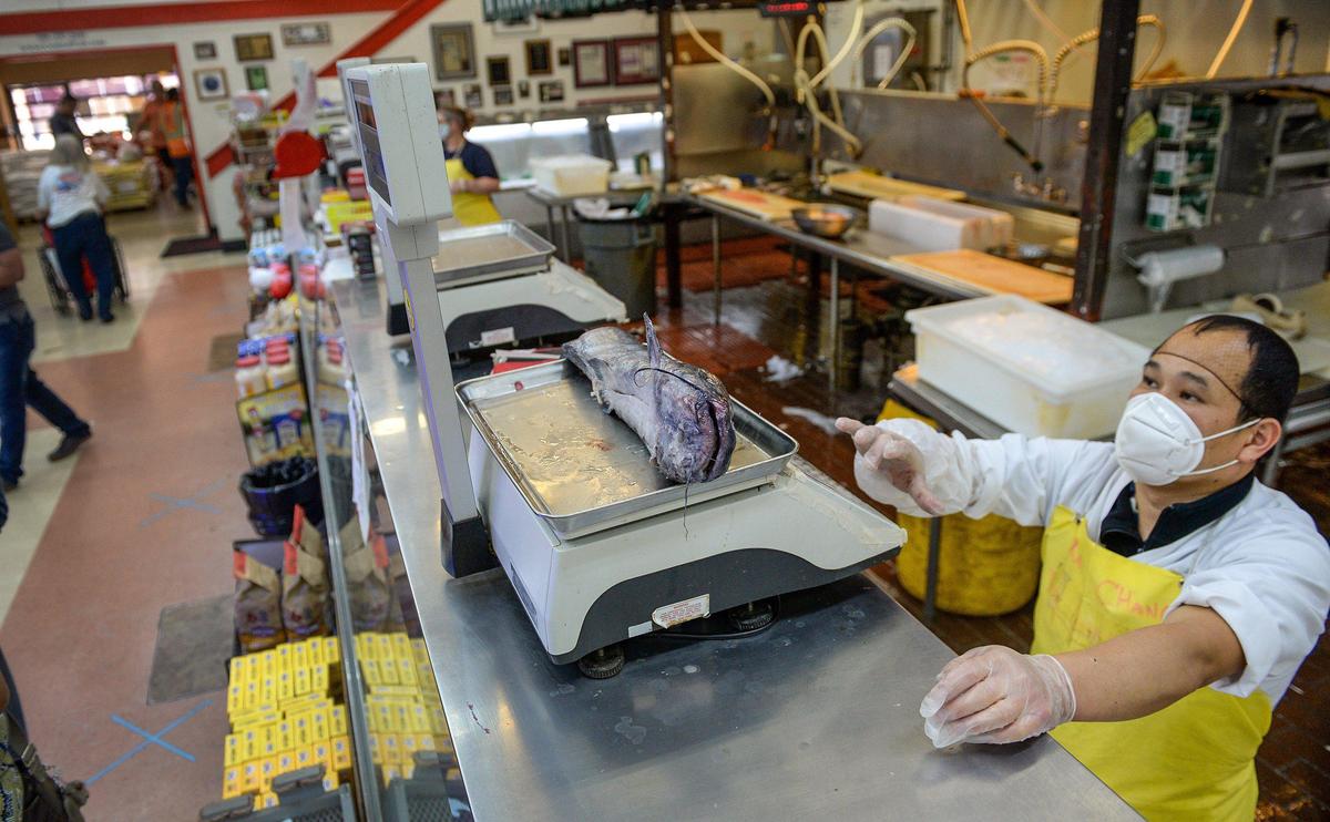 Xai Chang works behind the fish counter at Central Fish Co. in Chinatown on Tuesday, April 28, 2020. Although coronavirus orders have caused the business to take a hit, owner Morgan Doizaki says they’ve gotten creative to stay afloat during the economic downturn. But the virus is yet another strike to the Chinatown business area already hit hard by shut down roadways due to high-speed rail construction as well as the ongoing homeless problem.