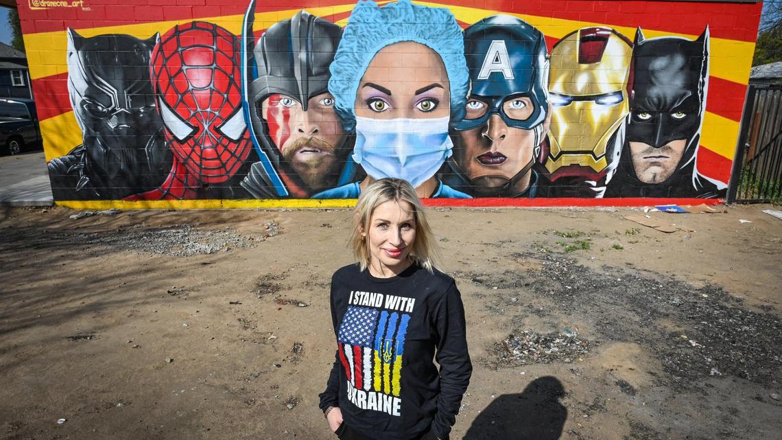 Nurse Oleksandra Korneta stands by the comic book hero mural near Community Regional Medical Center that symbolizes heroic work of all nurses, but is actually depicted in her likeness. She is Ukrainian and after her fight to help people through the pandemic, her struggle is not over as she worries for her family back home.