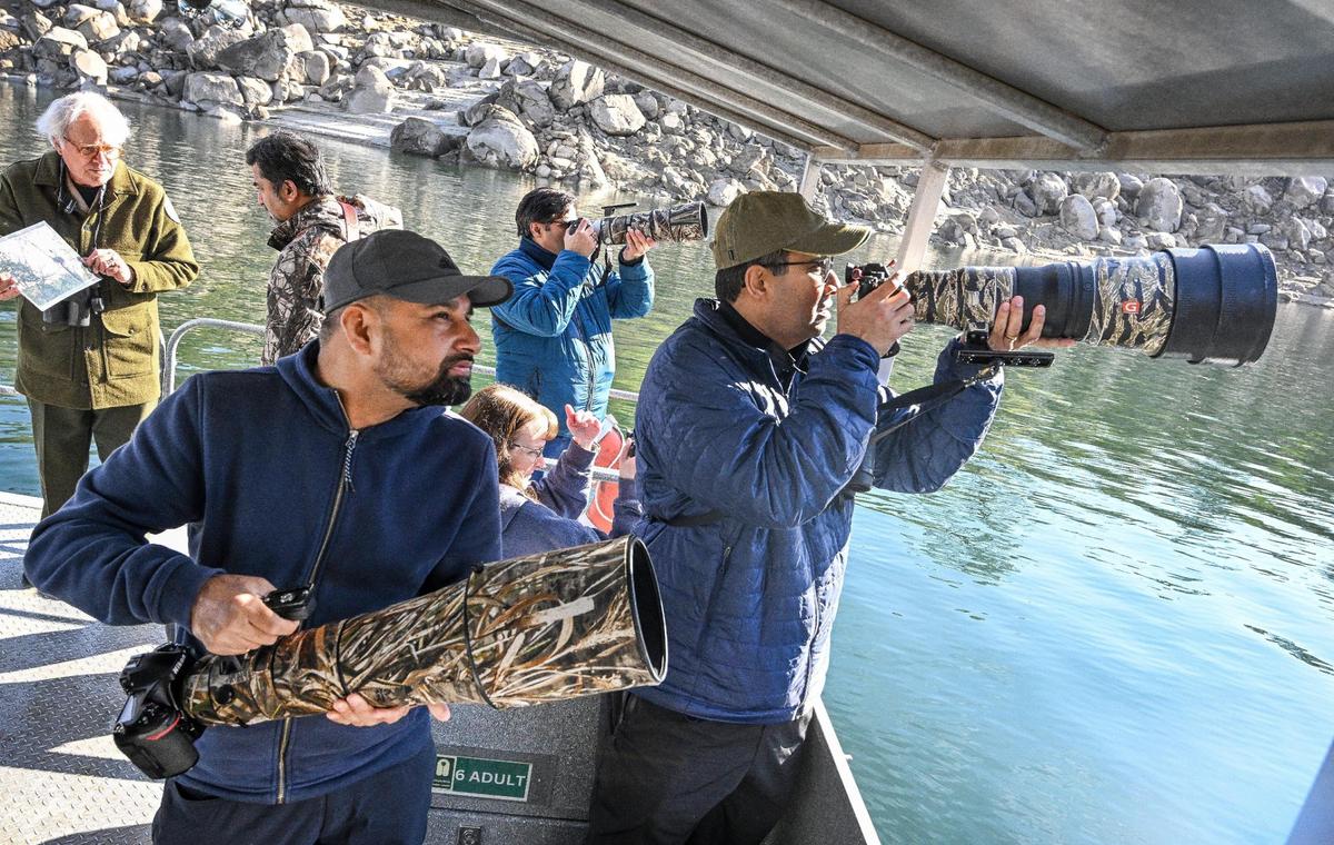 Photographers use telephoto lenses to try and get shots of a bald eagle while riding aboard a pontoon boat during the Millerton Lake eagle tour program on Sunday, Feb. 2, 2025.