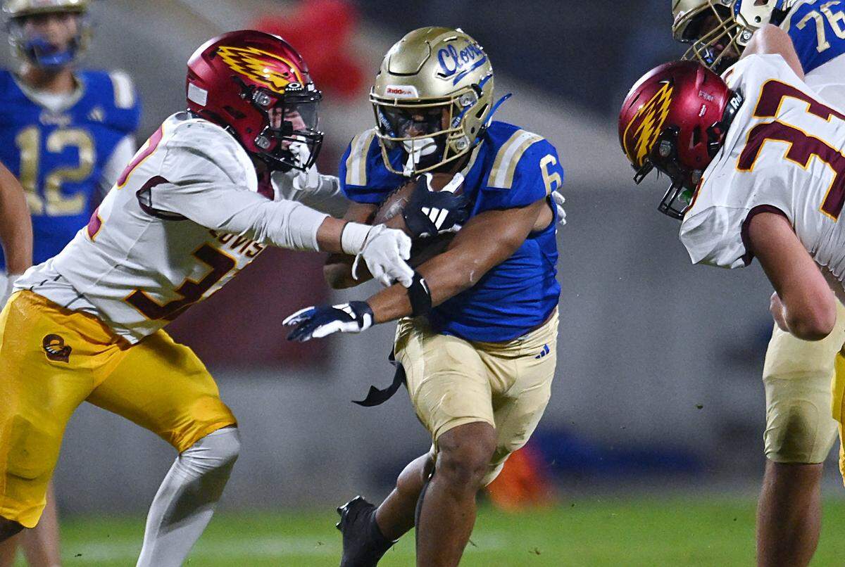 Clovis High's James Curoso, center, runs up the cneter with Clovis West's Cole Lawson to the left and Jake McPherson to the right Friday, Oct. 31, 2025 in Clovis. Clovis High led 21-10 at halftime.