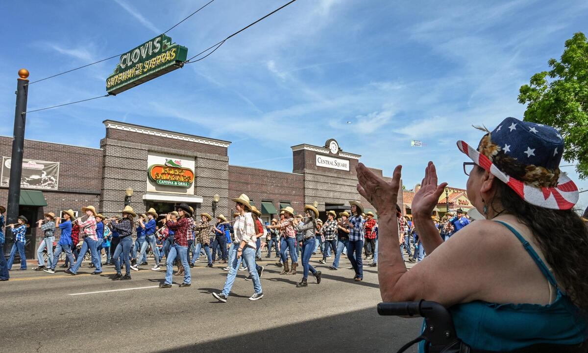 Parade-watchers cheer on the band as the Clark Intermediate School marching band passes under the Gateway to the Sierras sign on Clovis Avenue in Old Town Clovis during the 109th annual Clovis Rodeo Parade on Saturday, April 29, 2023.
