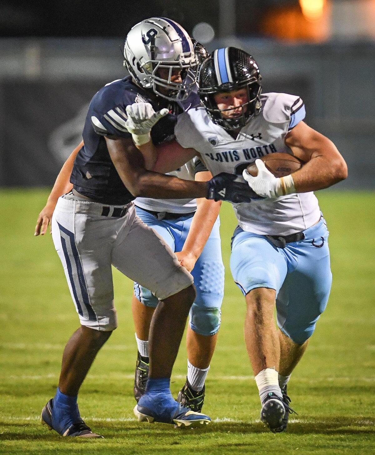 Clovis North’s McKay Madsen, right, tries to get by Clovis East’s Nathaniel Thompson on a run up the middle during their TRAC opener at Lamonica Stadium on Friday, Sept. 29, 2023.
