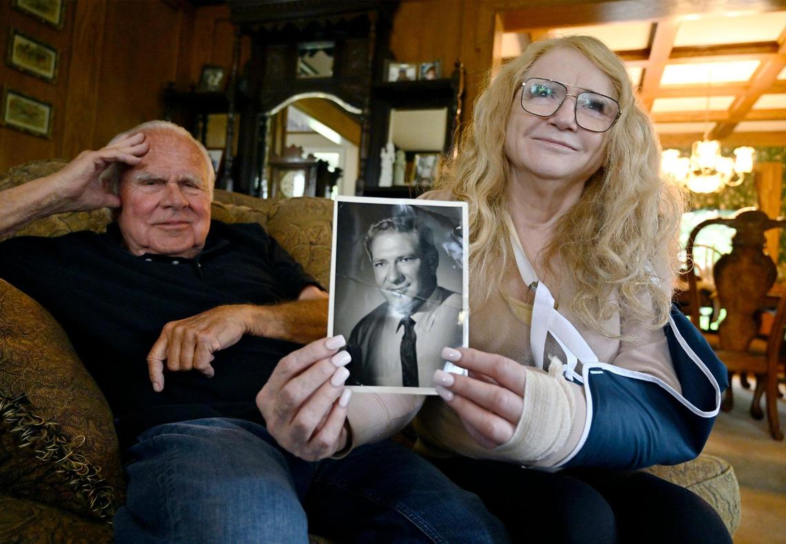 Barbara Moore Cota, right, with her partner Richard Hartman, left, holds a photo of her father George Moore Wednesday, May 3, 2023 in Fresno. A bracelet that belonged to Moore Cota’s father went missing last month after she required emergency medical services.