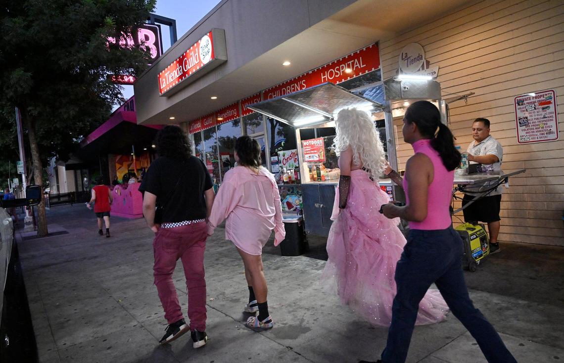 Pedestrians pass Jaime Gómez, a food vendor selling hot dogs on the sidewalk along Olive Avenue in Fresno’s Tower District Wednesday evening, July 19, 2023.