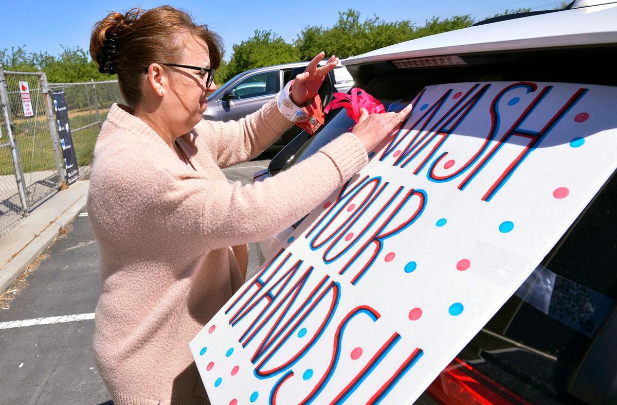 Kindergarten teacher Robin Johnson attaches decoration to her car before West Park Elementary staff held a drive-by parade throughout the community to wish their home-bound students well Thursday, April 2, 2020 in West Park, southwest of Fresno.