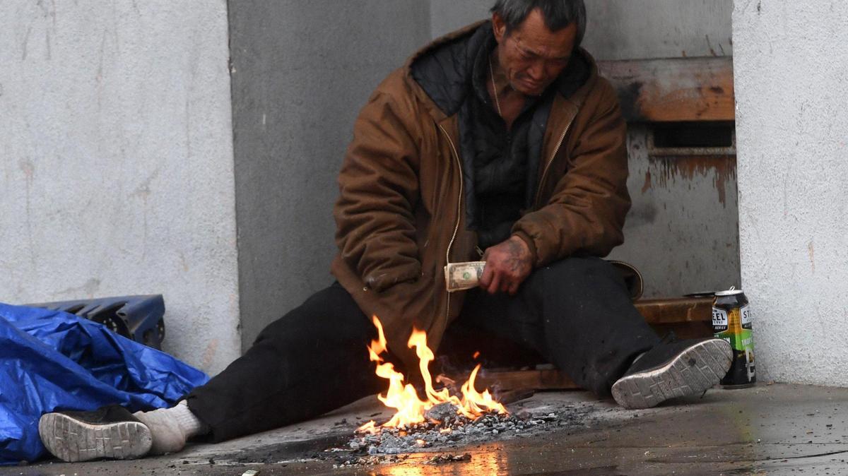 An unhoused man tries to keep warm in a doorway in downtown Fresno during a storm in 2021.